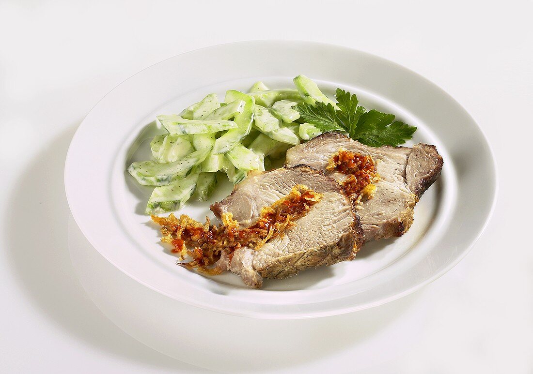 Slices of spit-roasted pork with cucumber salad