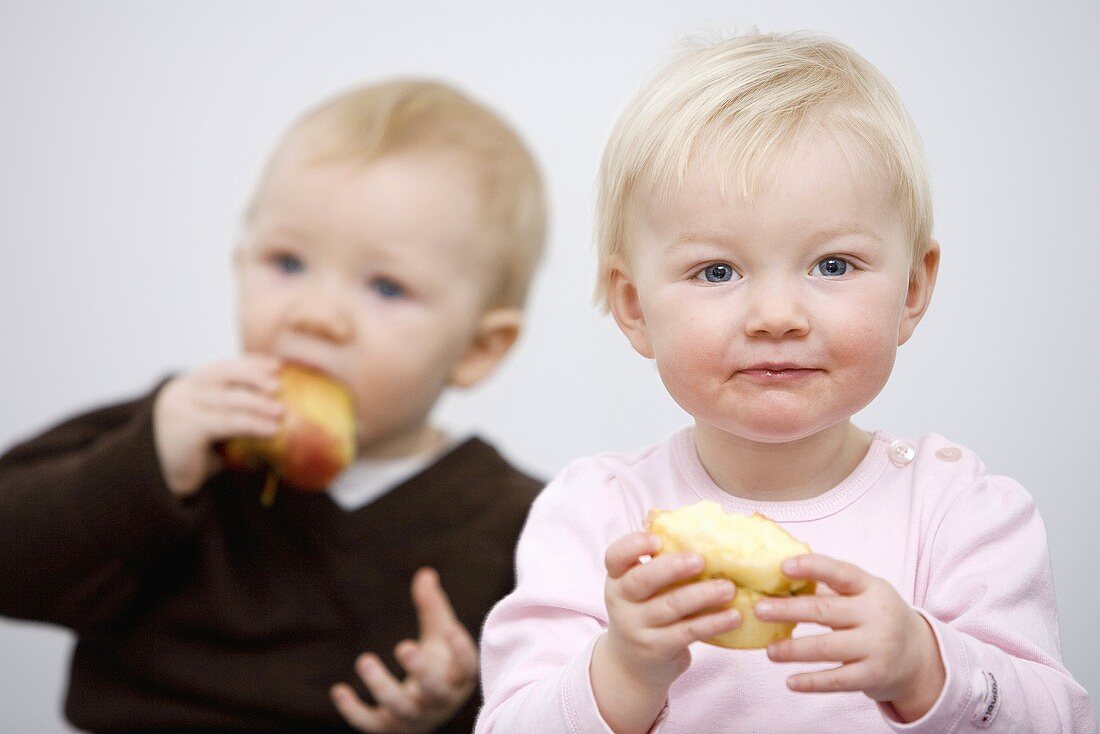 Zwei Babys essen Äpfel