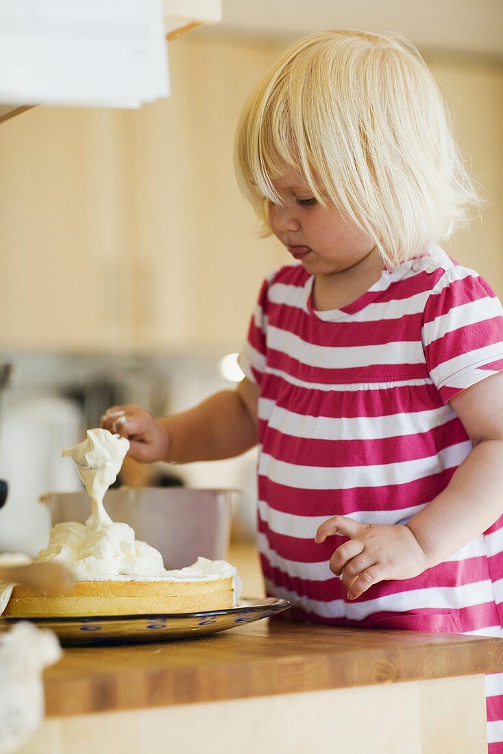 Small blond girl baking a cake