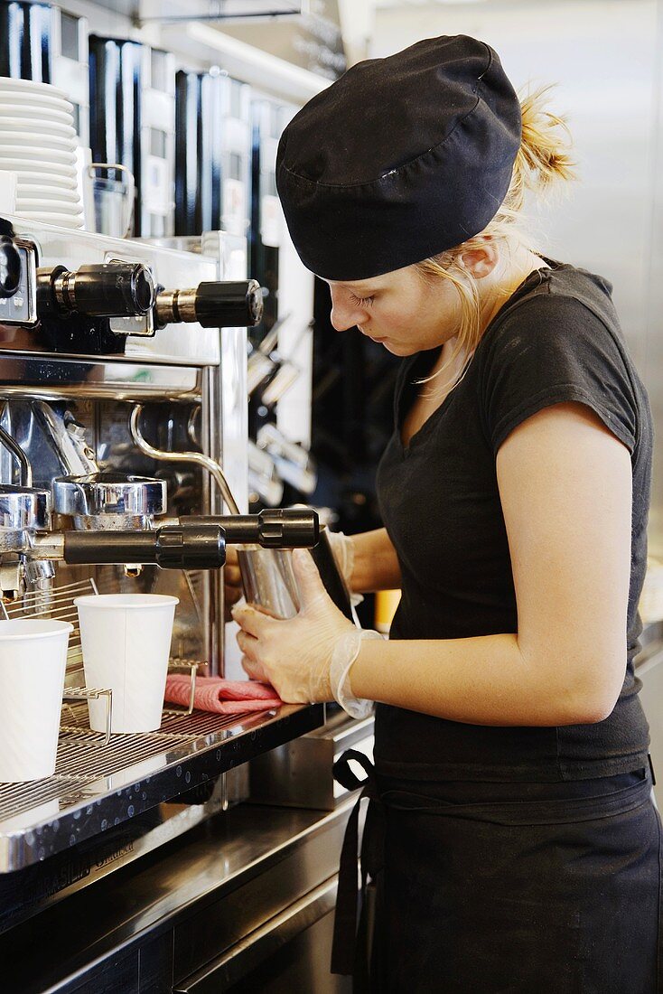 Waitress frothing milk in a café