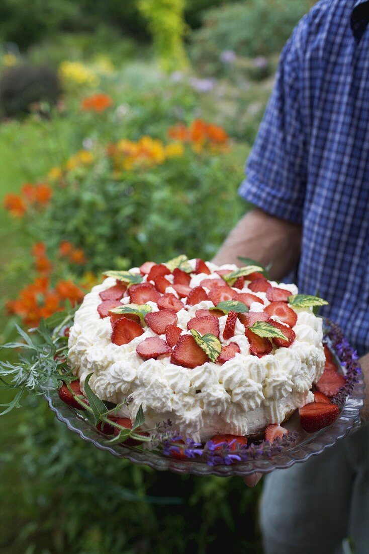 Man serving strawberry cream cake in garden
