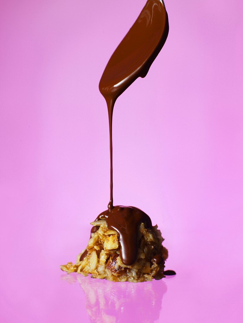 Chocolate sauce running from spoon onto biscuit