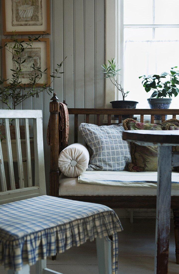 Esszimmer im schwedischen Stil mit einer gepolsterten Sitzbank aus Holz, hellgrauen Holzwänden und blau-weißen Textilien