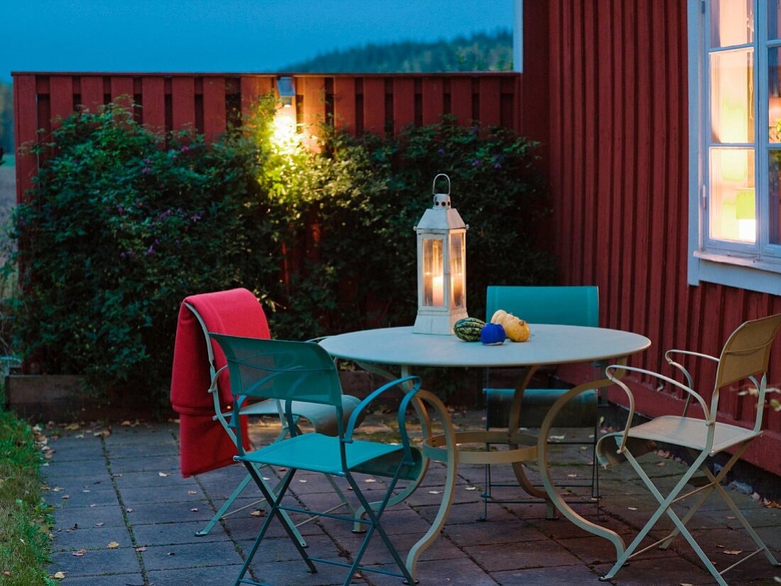 Gartentisch mit Laterne vor einem Haus