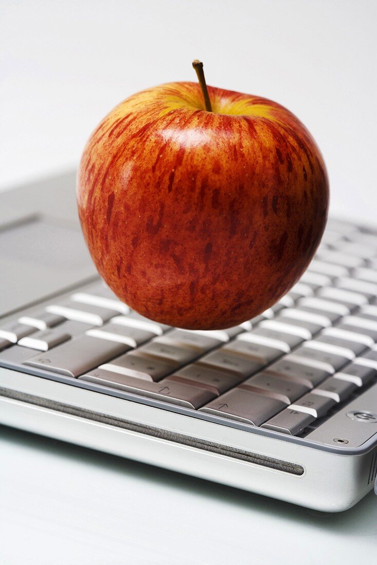 Roter Apfel schwebt über Laptop