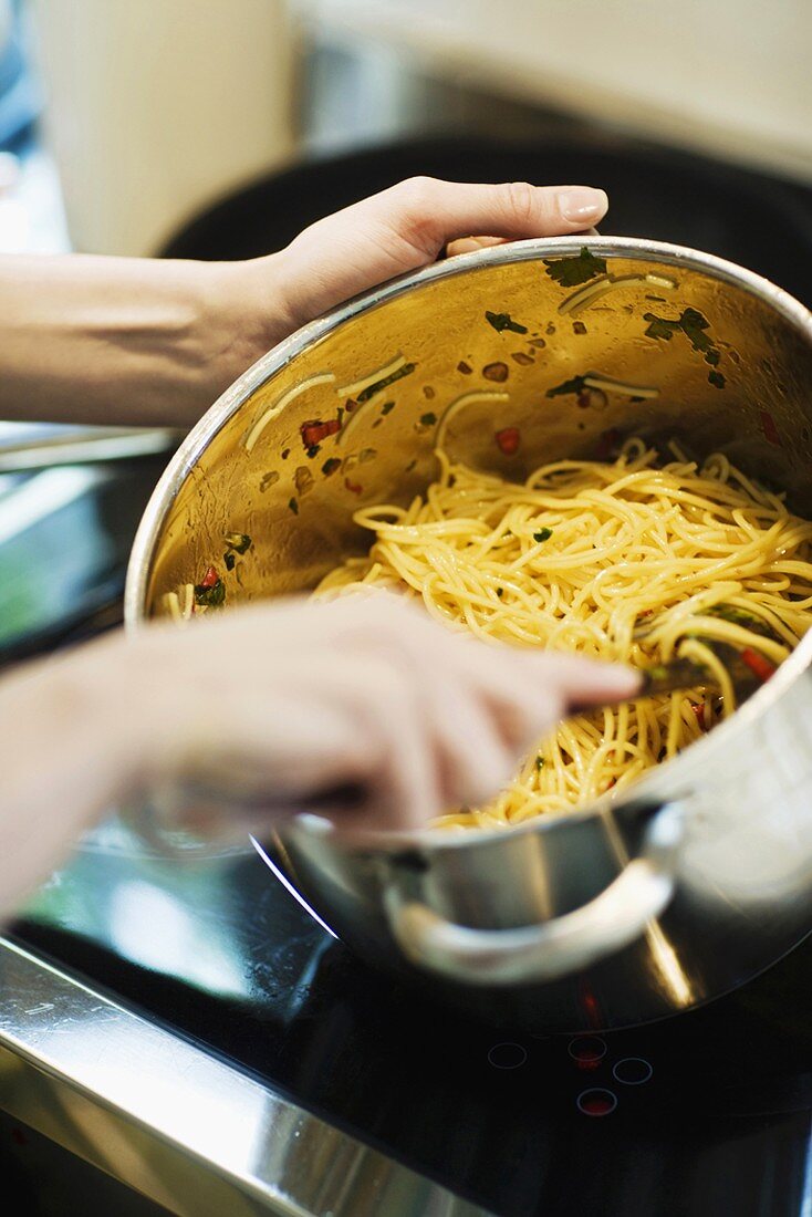 Spaghetti im Kochtopf mit Sauce vermischen