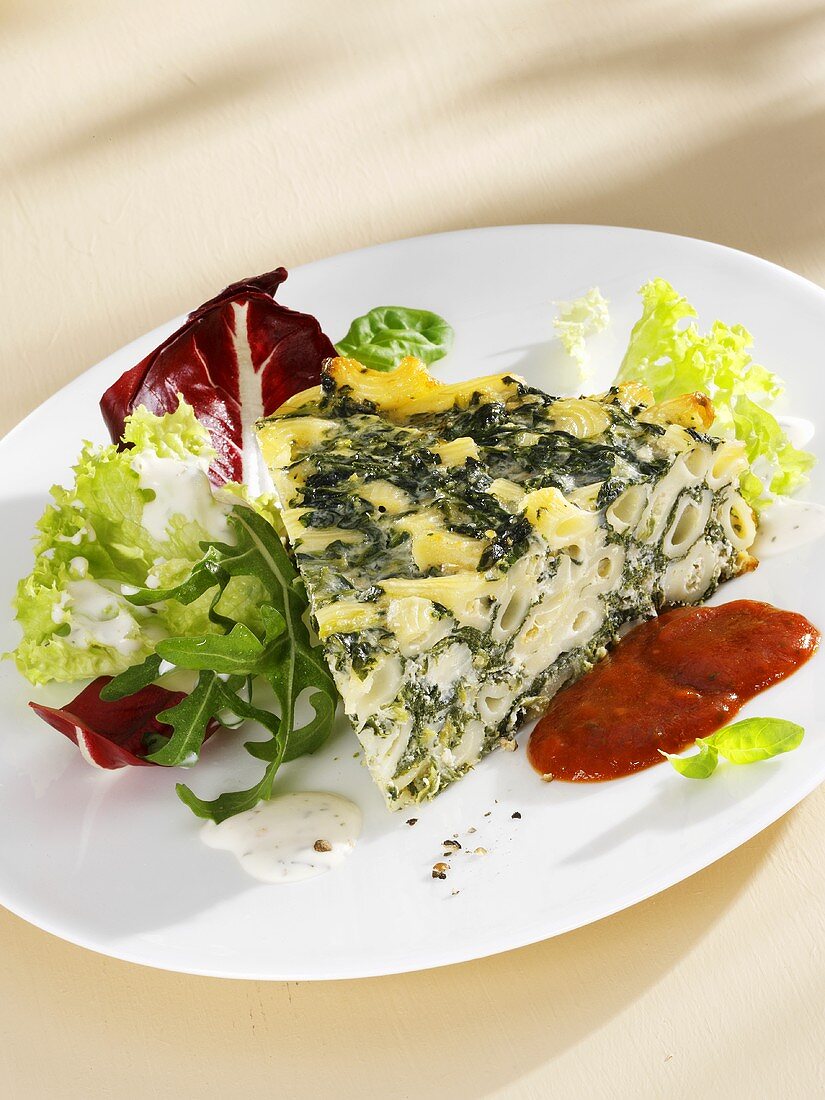 Piece of pasta, spinach and ricotta cake, salad garnish, tomato sauce