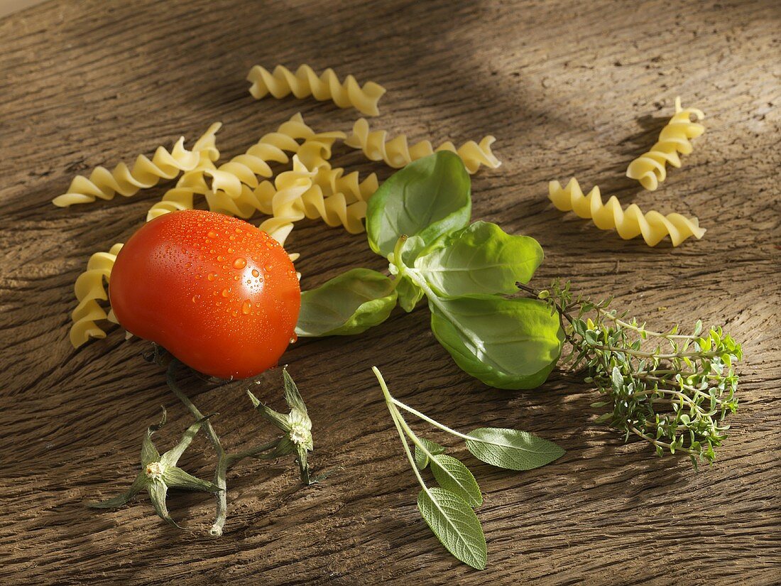 Fusilli, Tomate und Kräuter auf Holzbrett