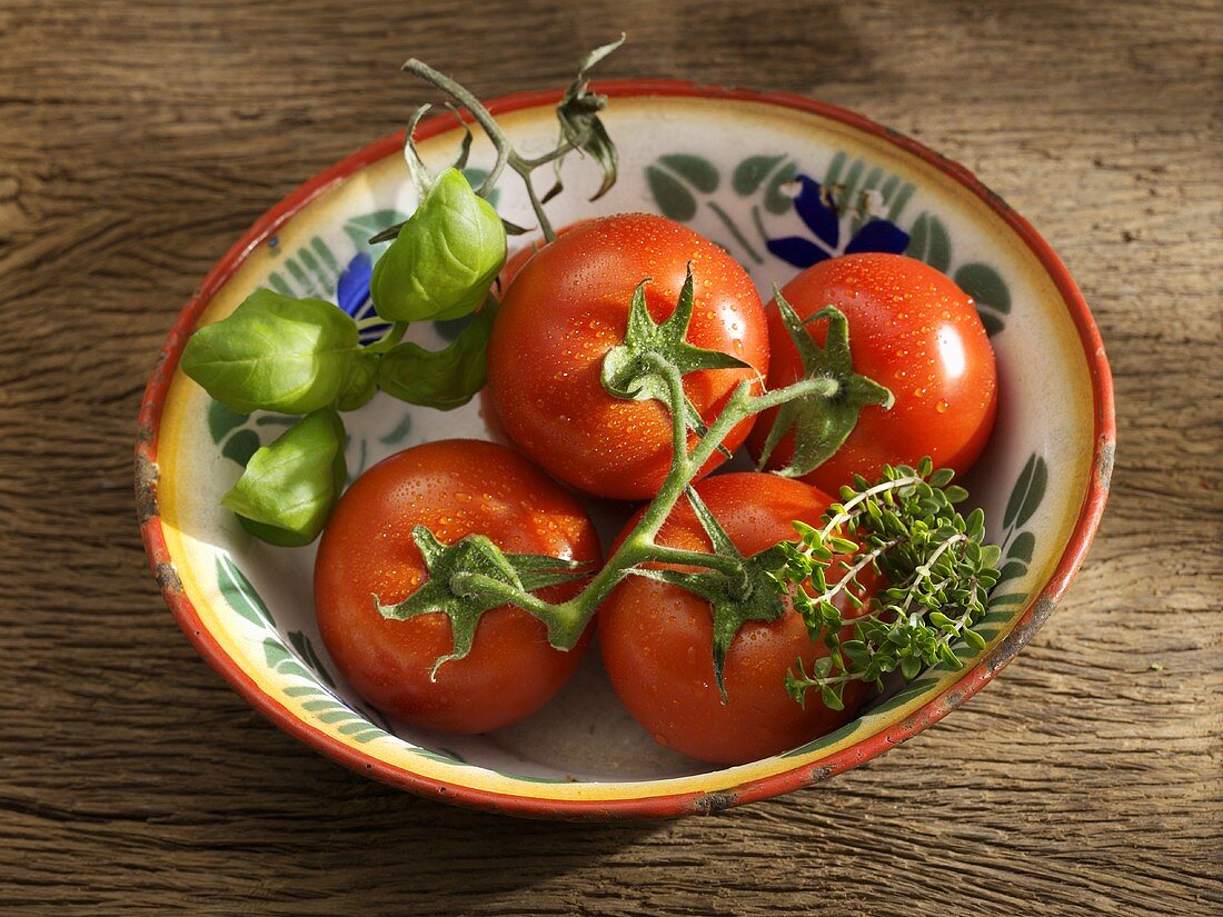 Tomatoes, basil and thyme in rustic metal dish