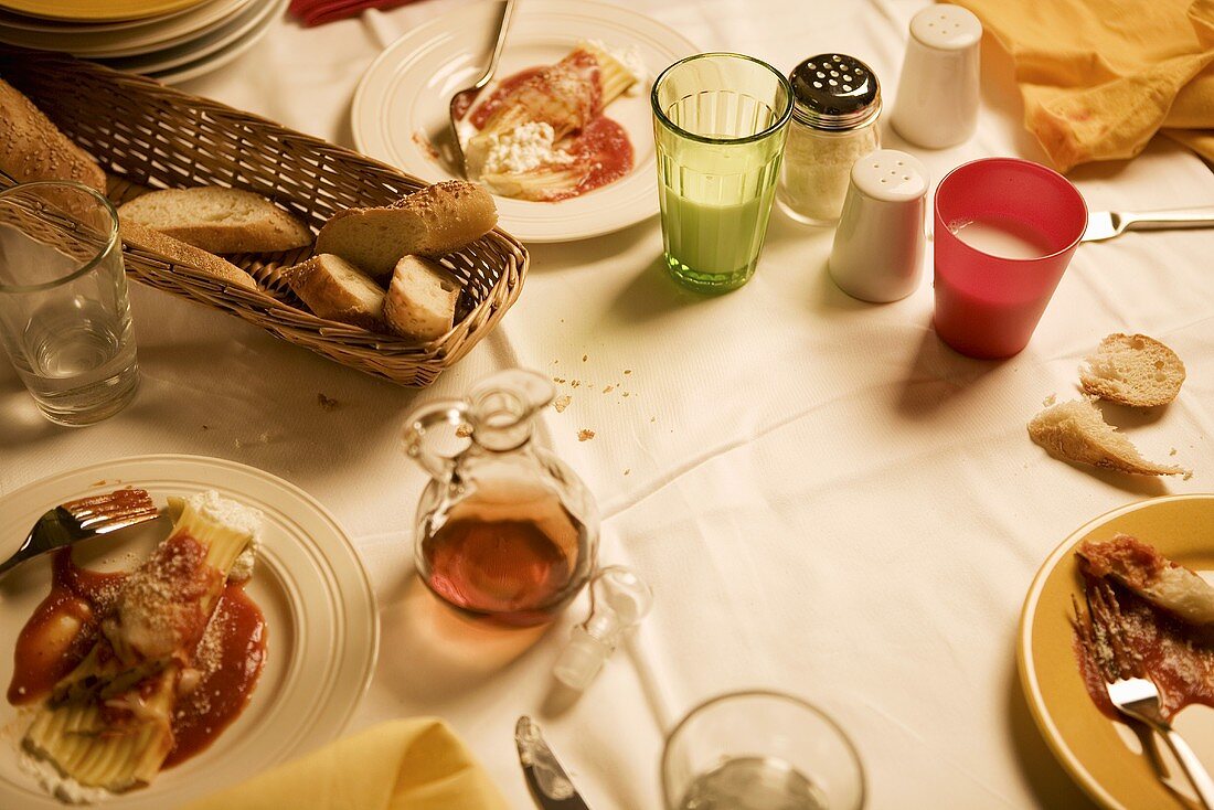 Pasta dish (manicotti) and bread on laid table (Italy)