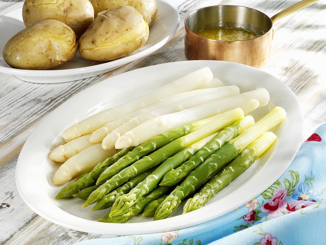 Green and white asparagus on platter, potatoes, butter