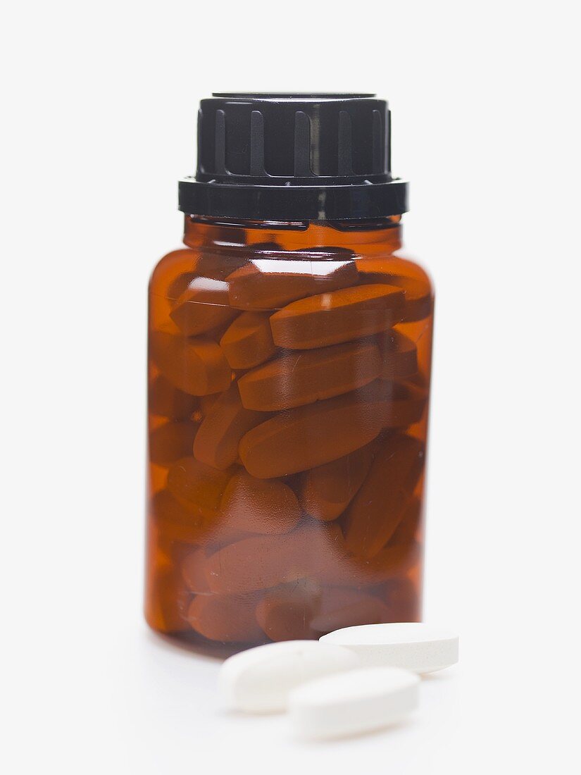 Tabletten im Medizinglas und daneben
