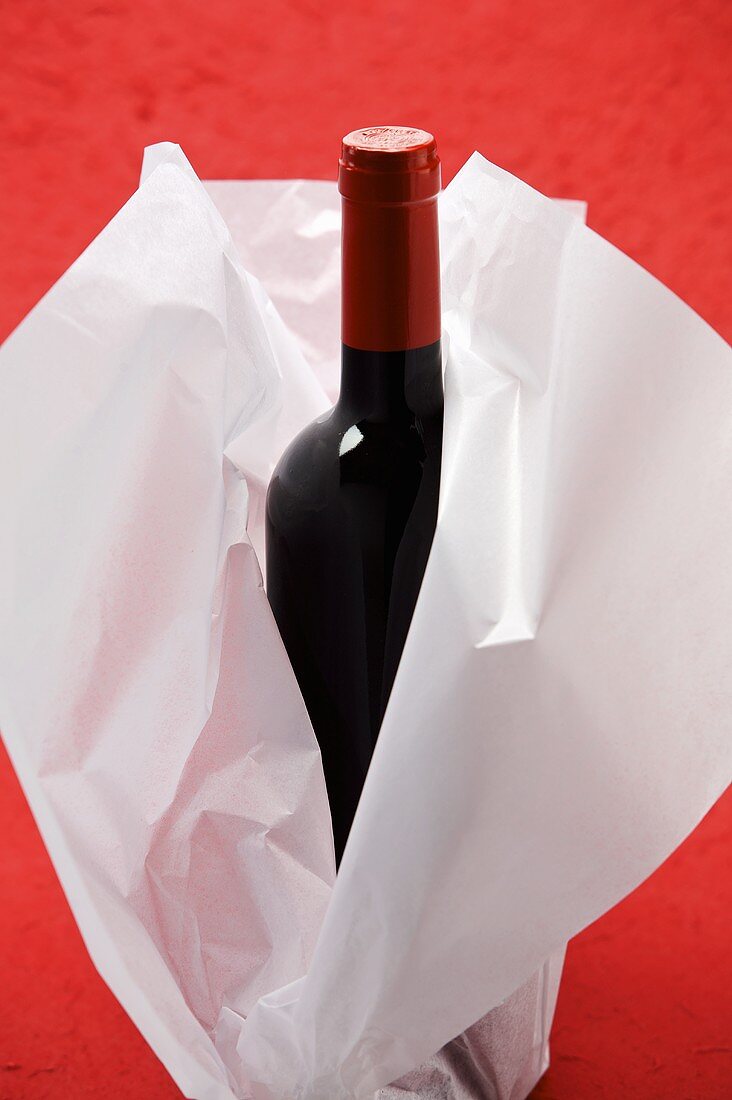 A bottle of red wine wrapped in tissue paper