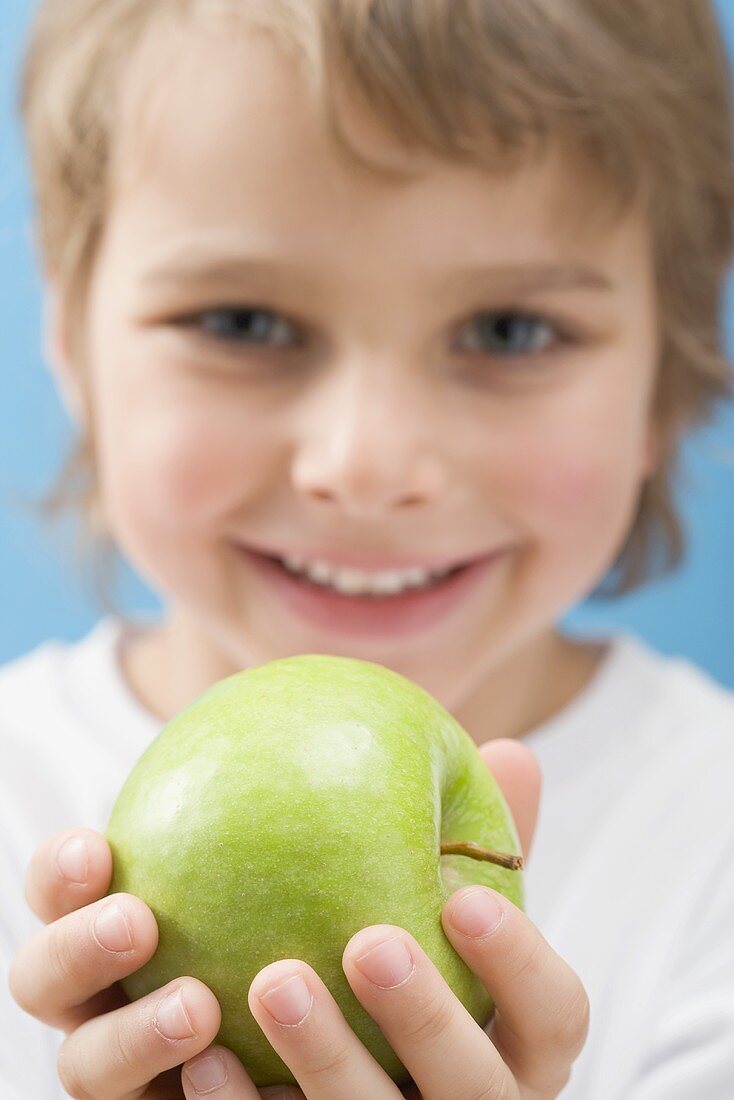 Little boy holding green apple