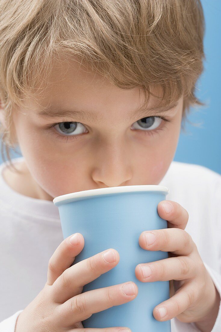 Little boy drinking milk out of blue beaker