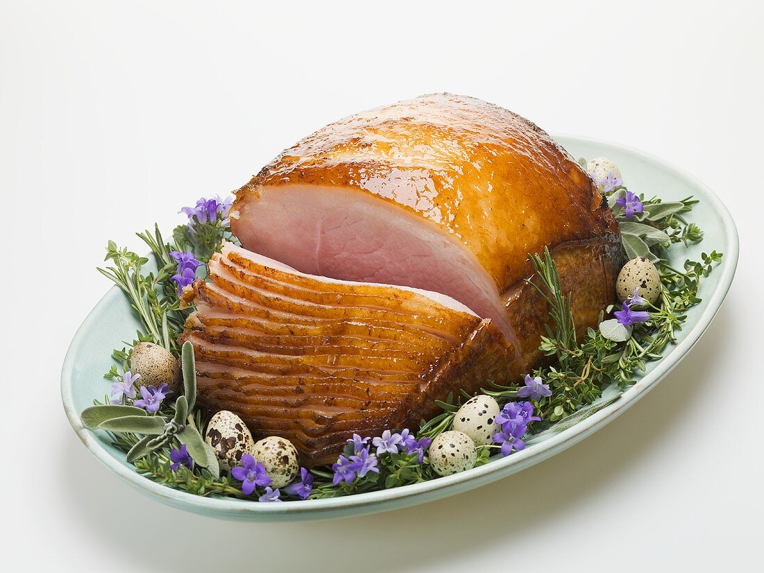 Glazed roast ham surrounded by herbs, for Easter