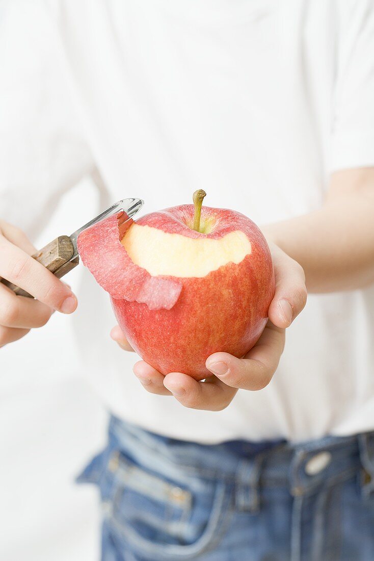 Kind schält Apfel