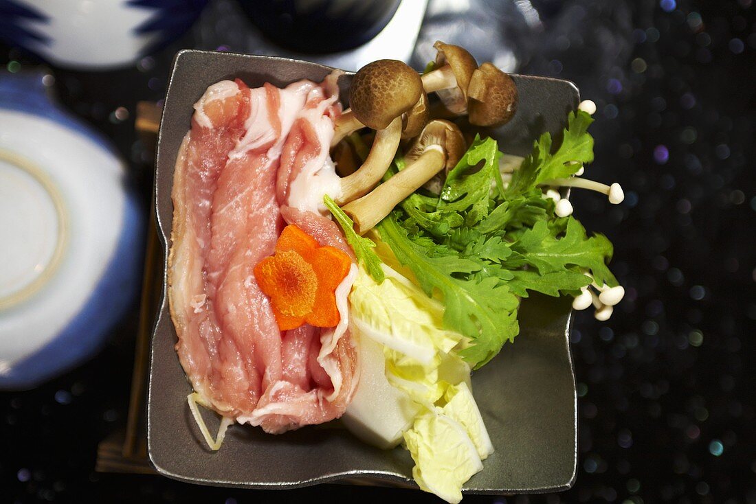 Zutaten für Sukijaki (Schweinefleisch, Kohl, Inoki-Pilze und Karotten)