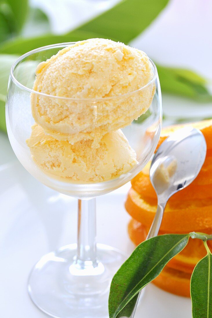 Two scoops of orange ice cream in a glass