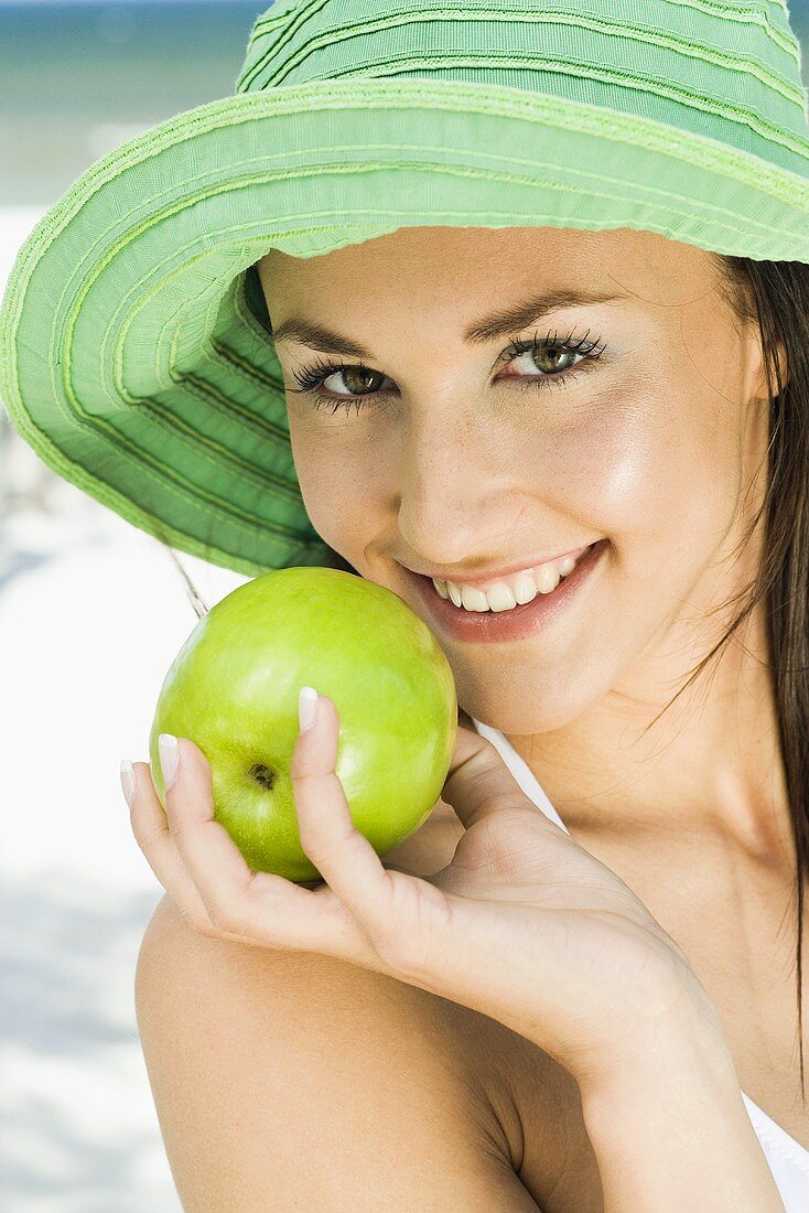 Junge Frau mit Sommerhut und grünem Apfel