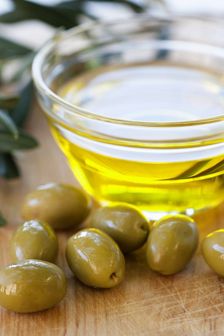 Grüne Oliven und ein Schälchen Olivenöl