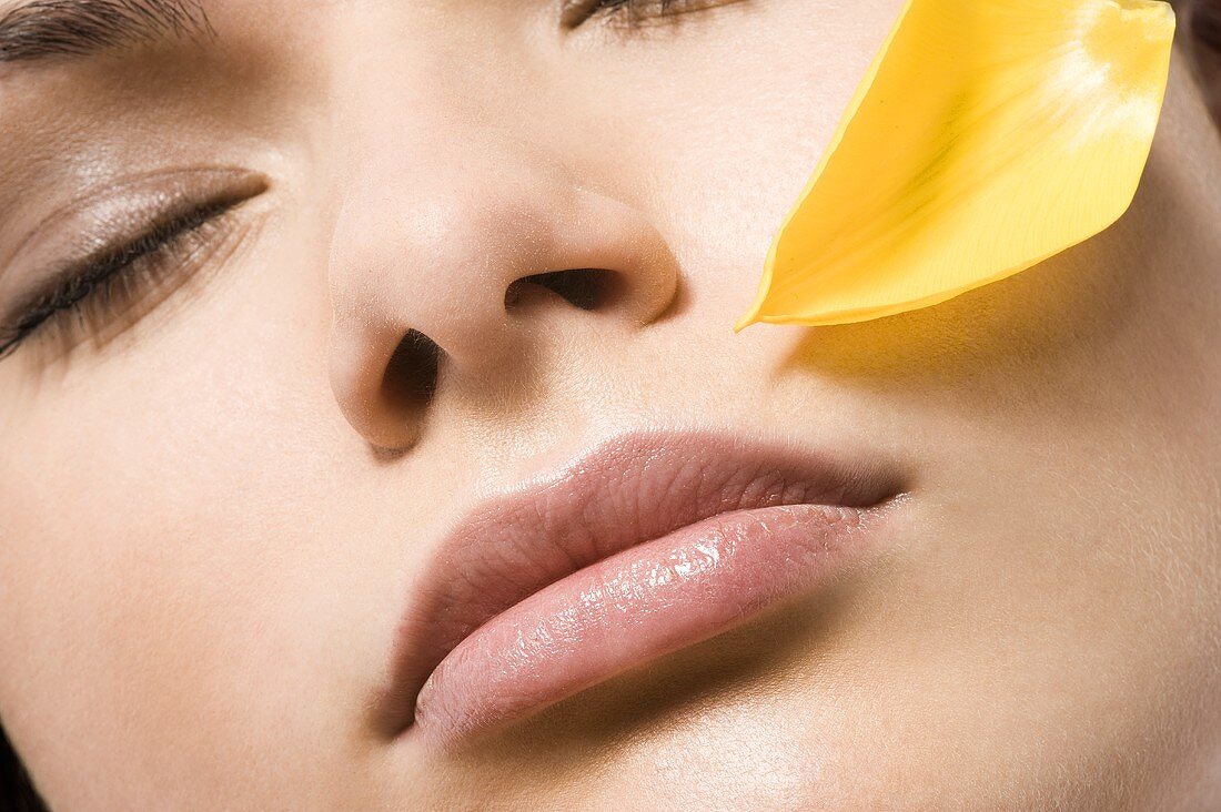 Young woman's face with flower petal (close-up)