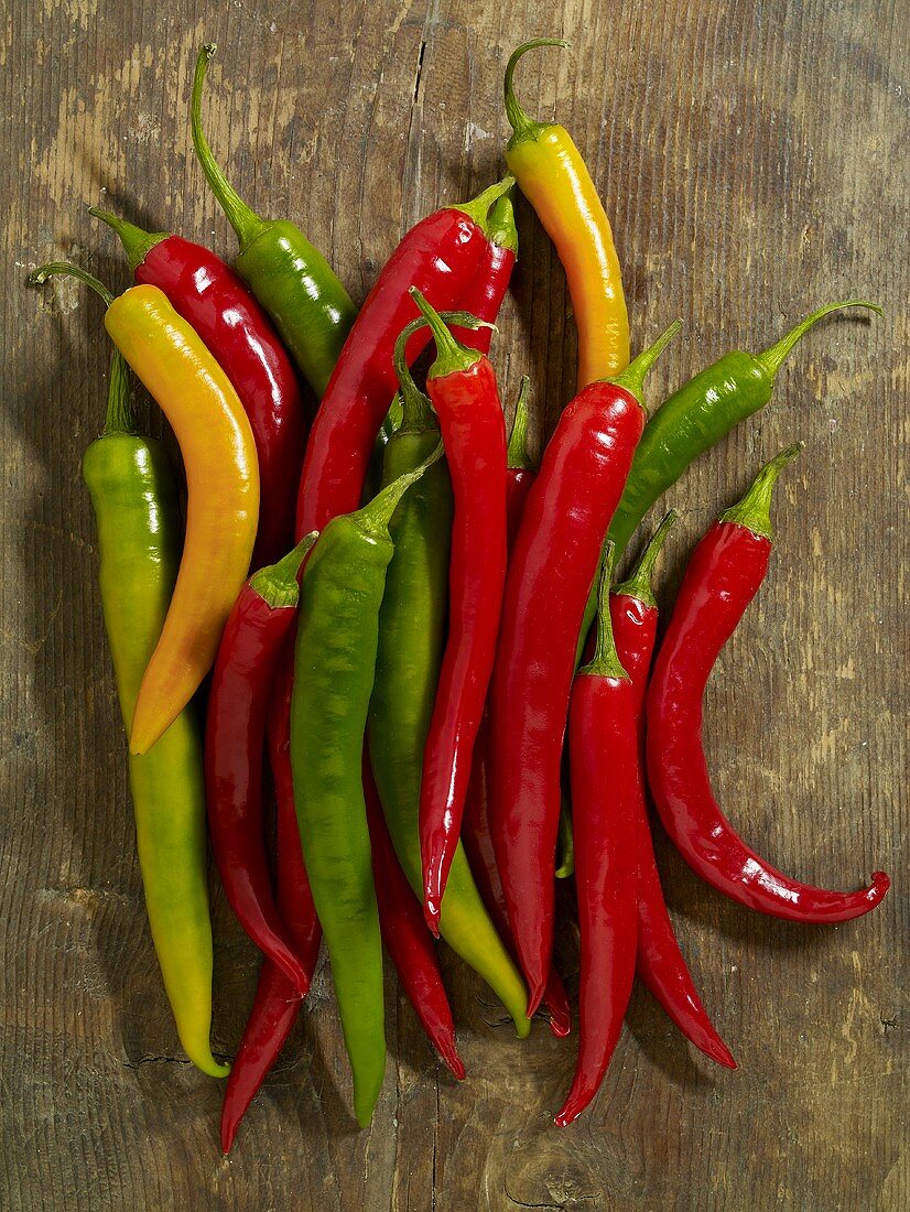 Fresh chillies (red, yellow, green) on wooden background