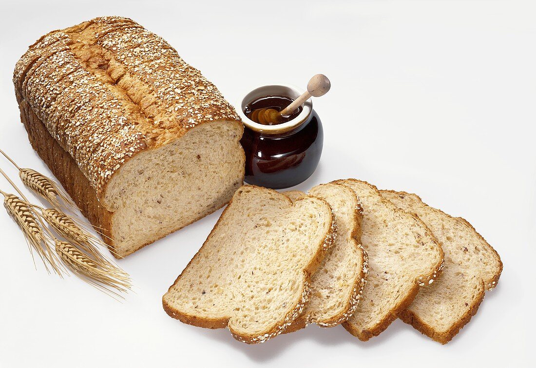 Sliced Loaf of Whole Wheat Bread with Honey Jar