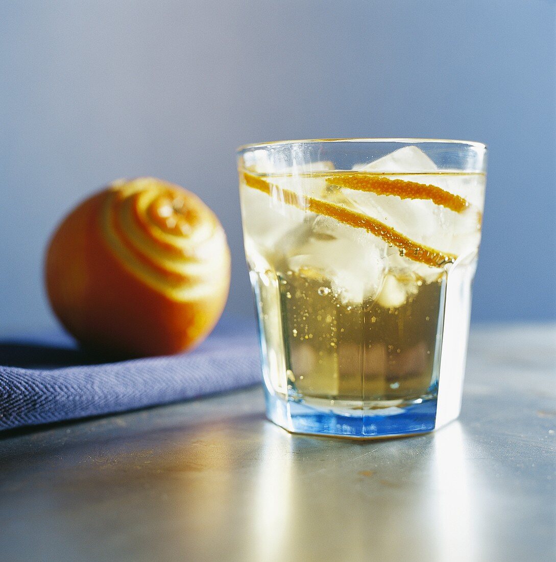 Drink mit Orangenschale und Eiswürfeln
