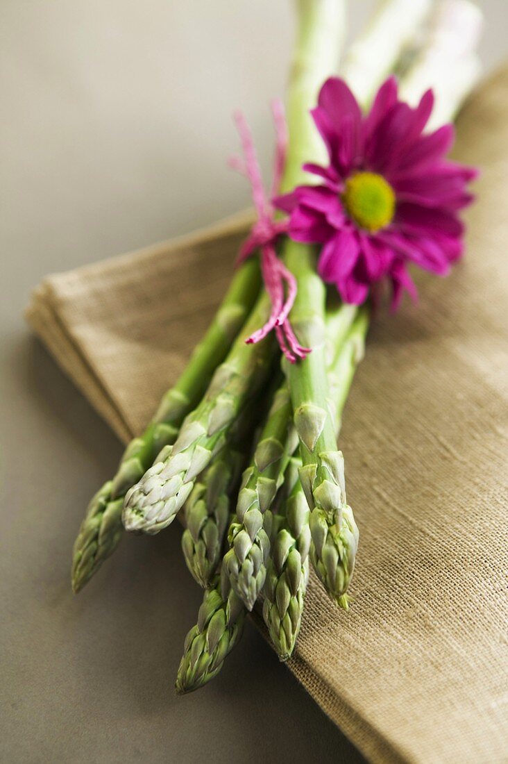 Grüner Spargel mit Gerbera auf Stoffserviette