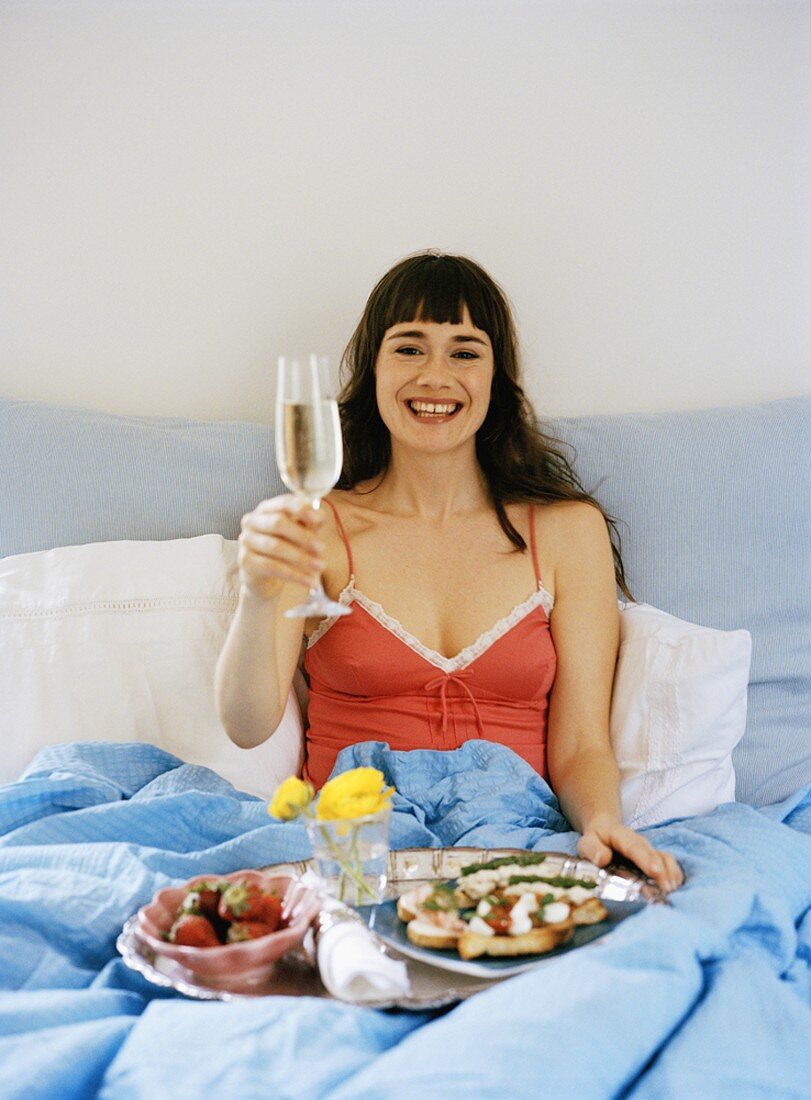 Woman with champagne breakfast in bed