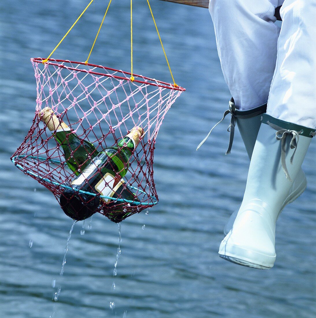 Person am Bootssteg hält Netz mit Bierflaschen