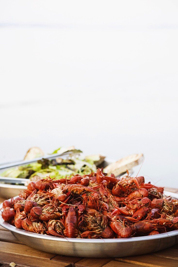 Crayfish and salad on a wooden table at the beach