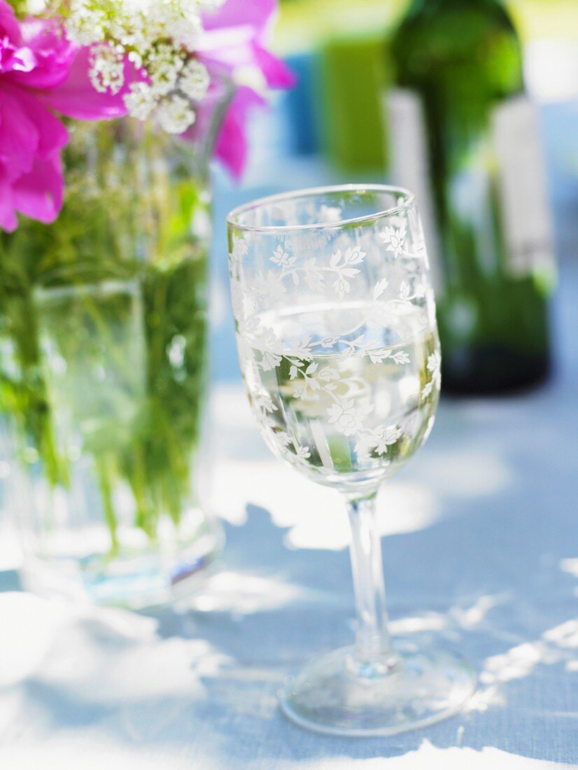 Weissweinglas auf sommerlichem Tisch