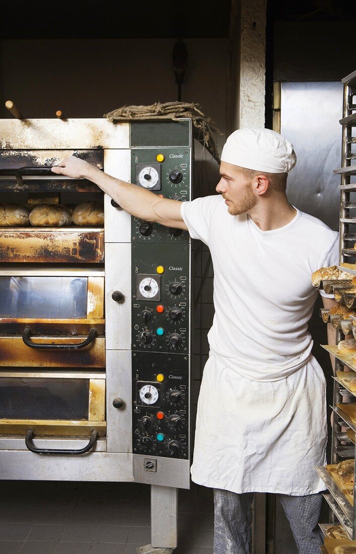 Baker checking bread in oven