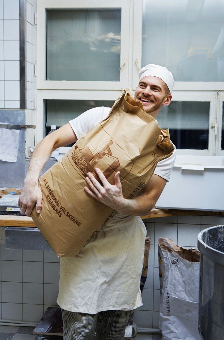 Baker holding sack of flour