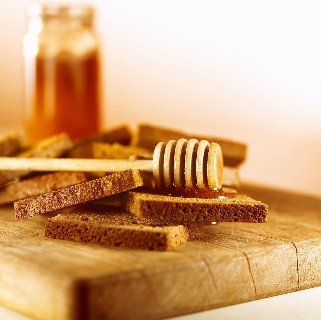 Vollkornbrot mit Honig und Honiglöffel auf einem Brett