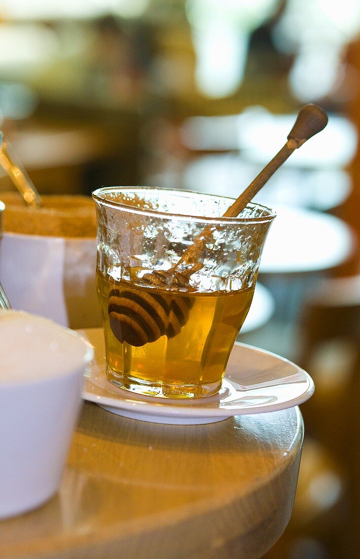 A glass of honey with honey dipper