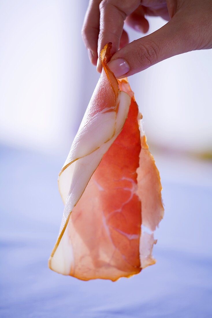 Woman holding a slice of raw ham in her hand