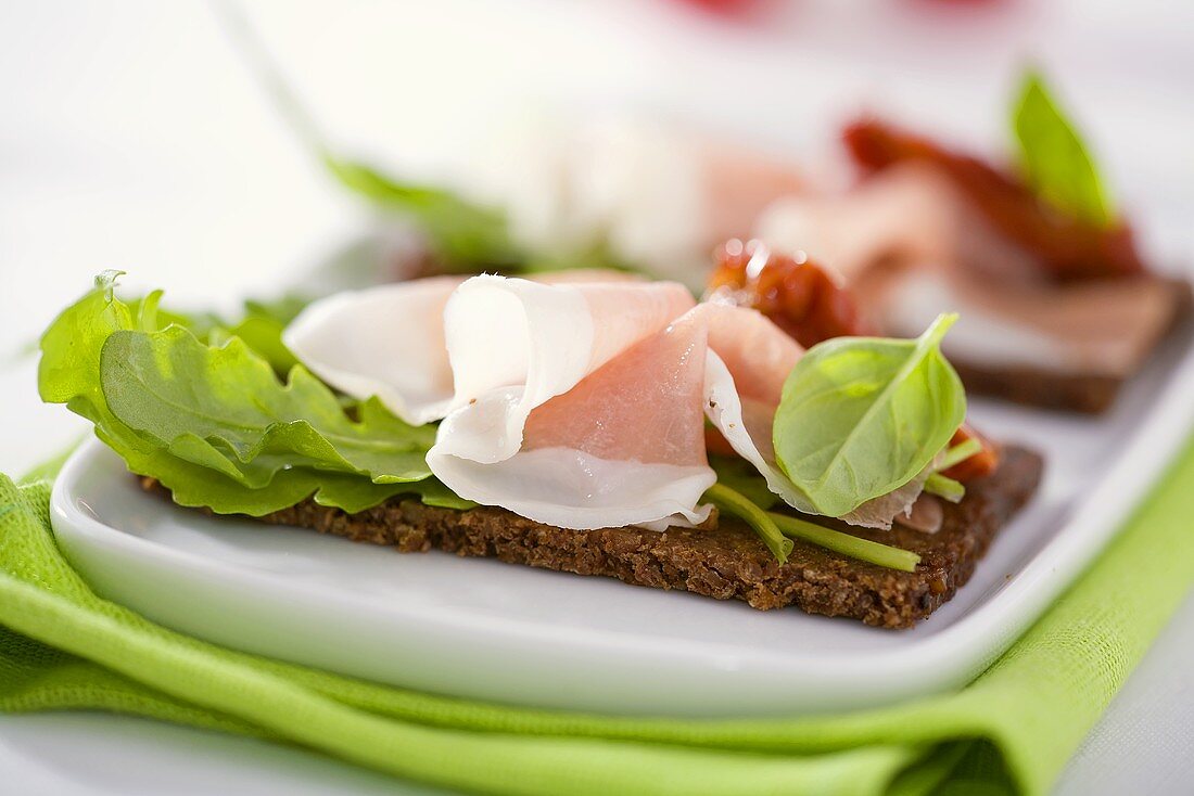 Raw ham, rocket and dried tomatoes on wholemeal bread