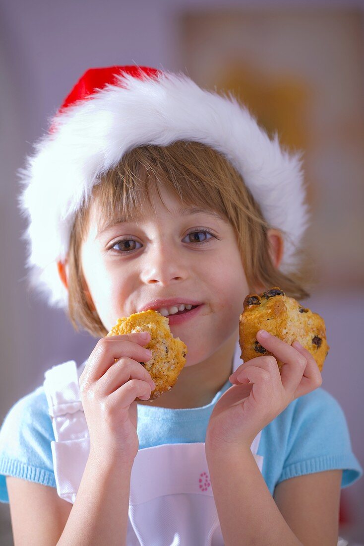 Little girl in Santa hat eating raisin biscuits
