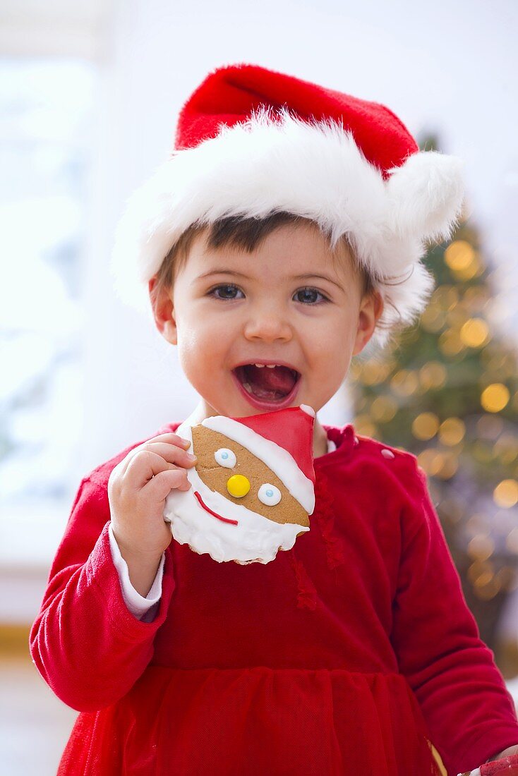 Little girl in Santa hat eating a biscuit