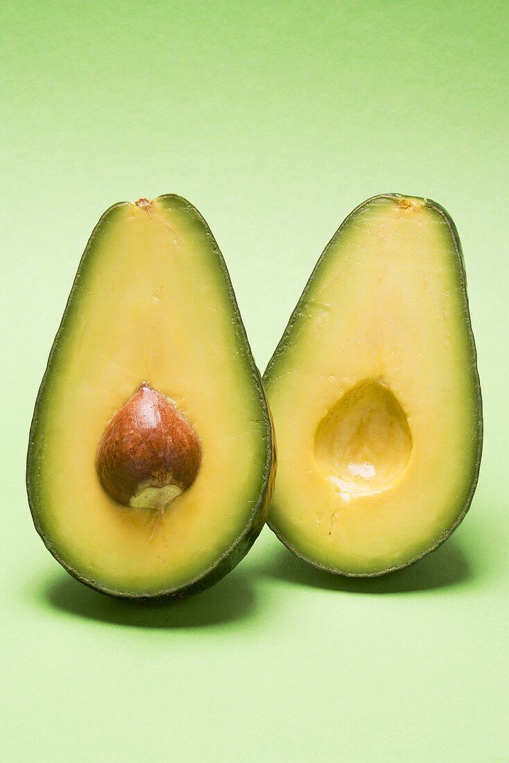 Avocado, halved, against green background