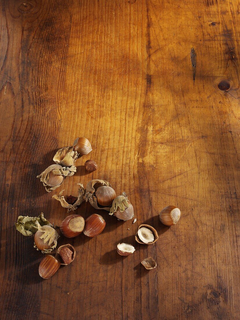 Whole Hazelnuts with One Cracked Open on Wood