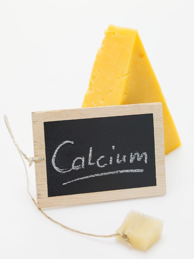 Schiefertafel mit Schrift Calcium vor Stück Cheddar