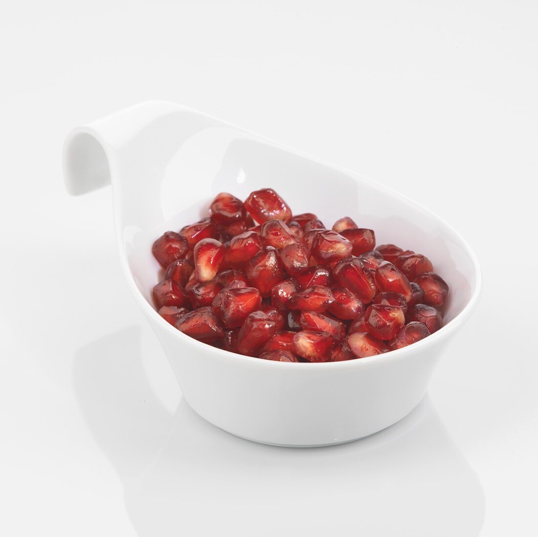 Pomegranate seeds in white dish