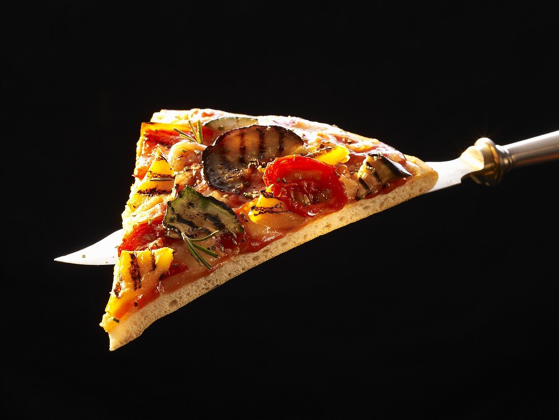 A slice of grilled vegetable pizza on knife
