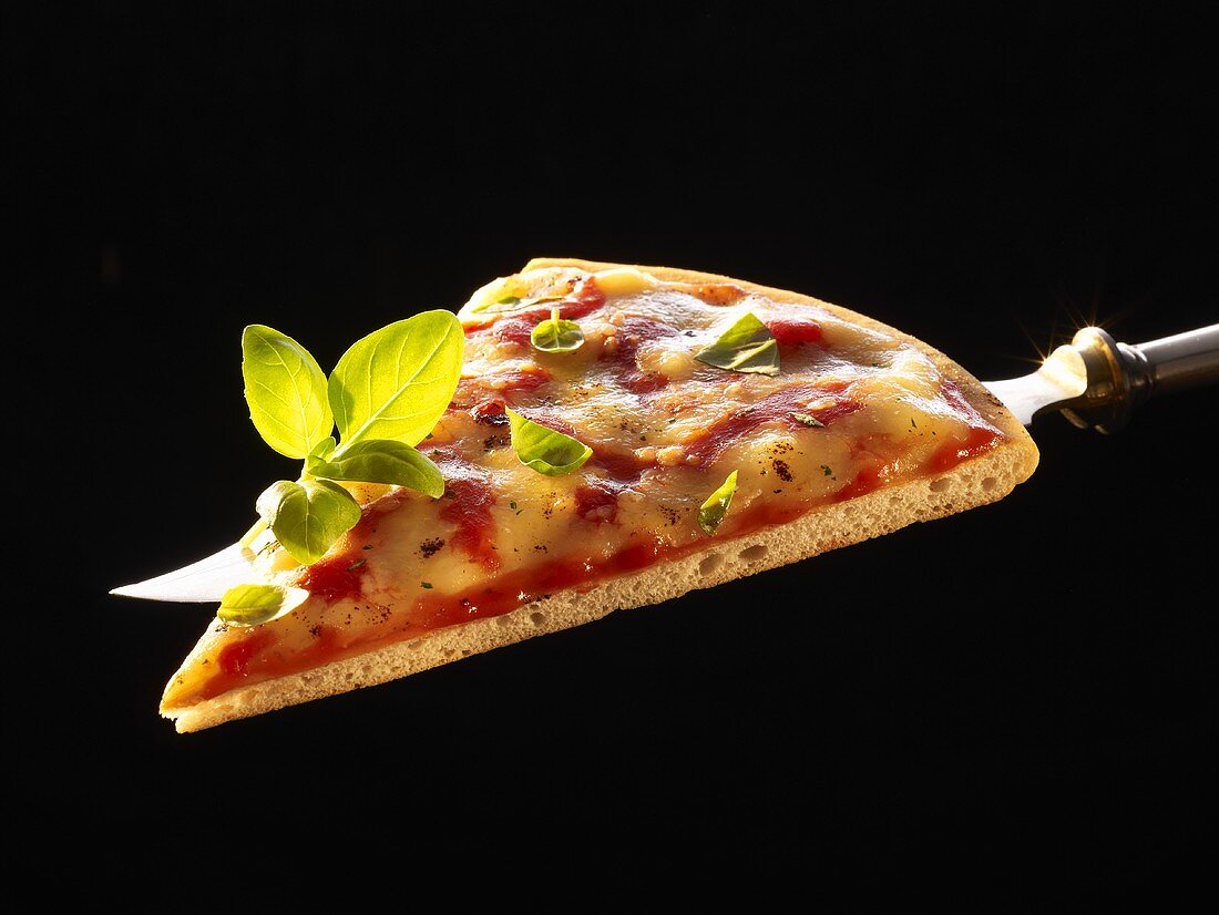 A slice of pizza Margherita with basil on knife