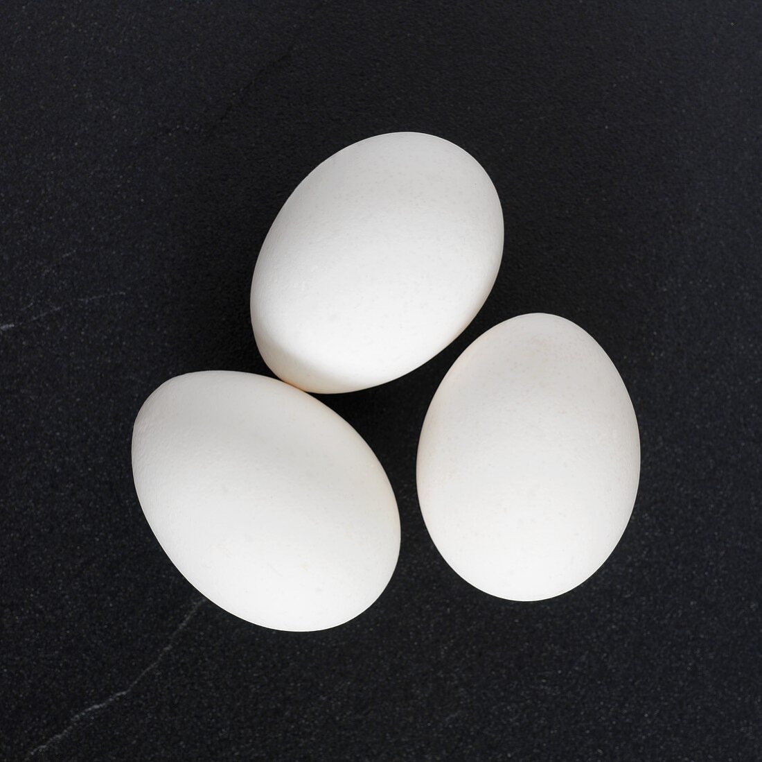 Three white eggs on black background