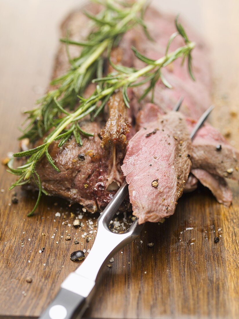 Roast saddle of venison with rosemary, piece on meat fork